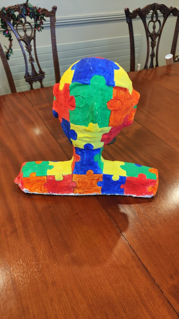 A colorful bust made by puzzle pieces on a wood table