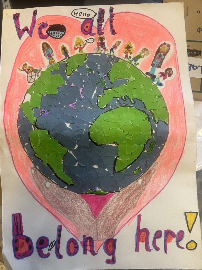 Colorful drawing of a globe with the caption We all belong here, emphasizing unity, belonging, and global inclusivity.